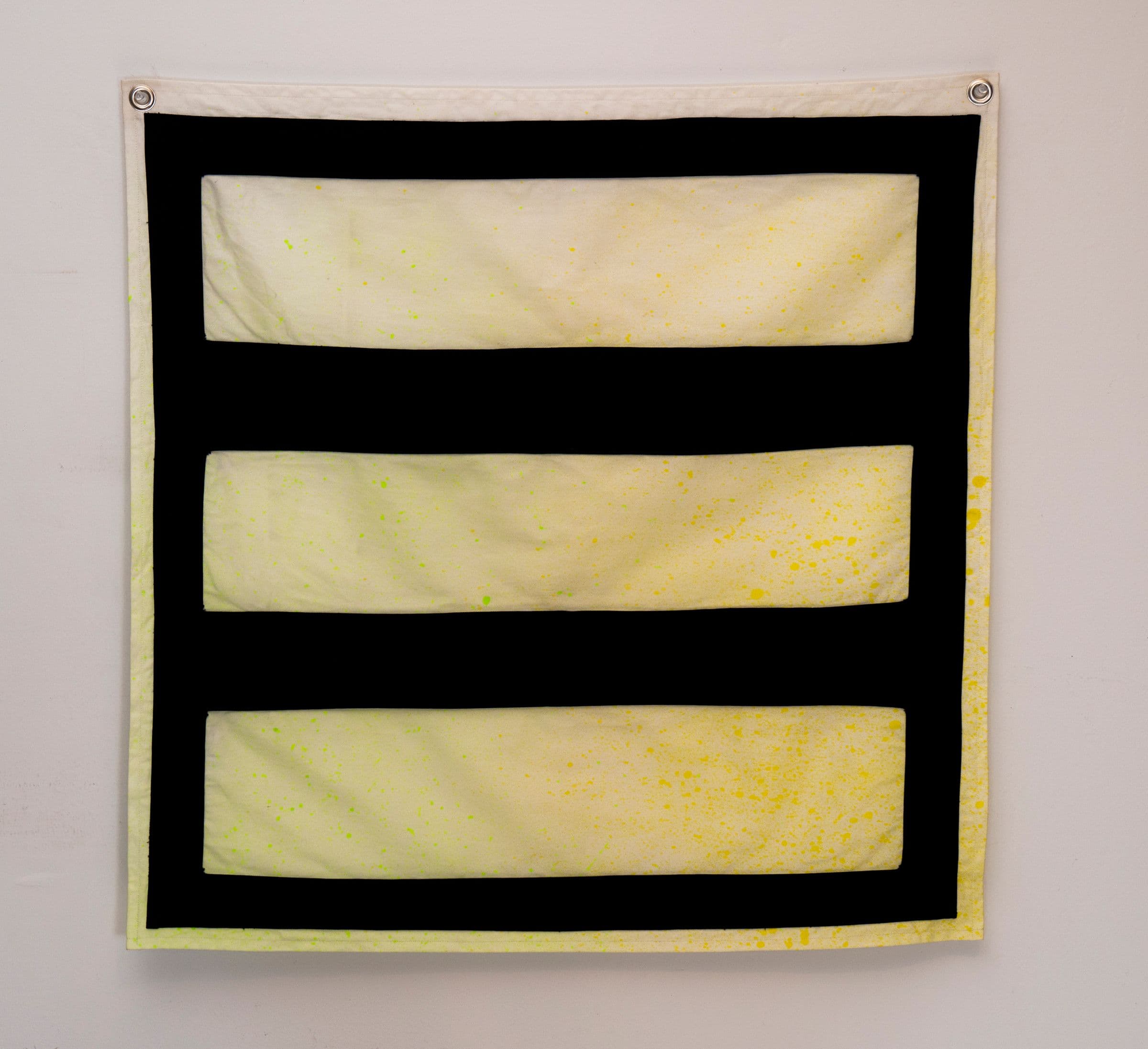 a square canvas piece with grommets in each corner. lines create a shifting pattern