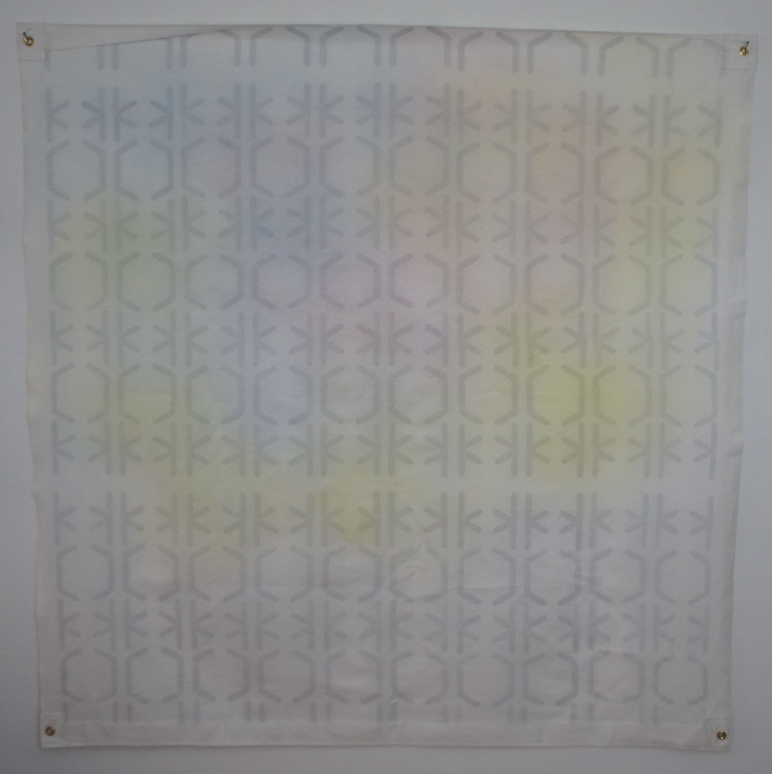 a square canvas piece with grommets in each corner. lines create a shifting pattern