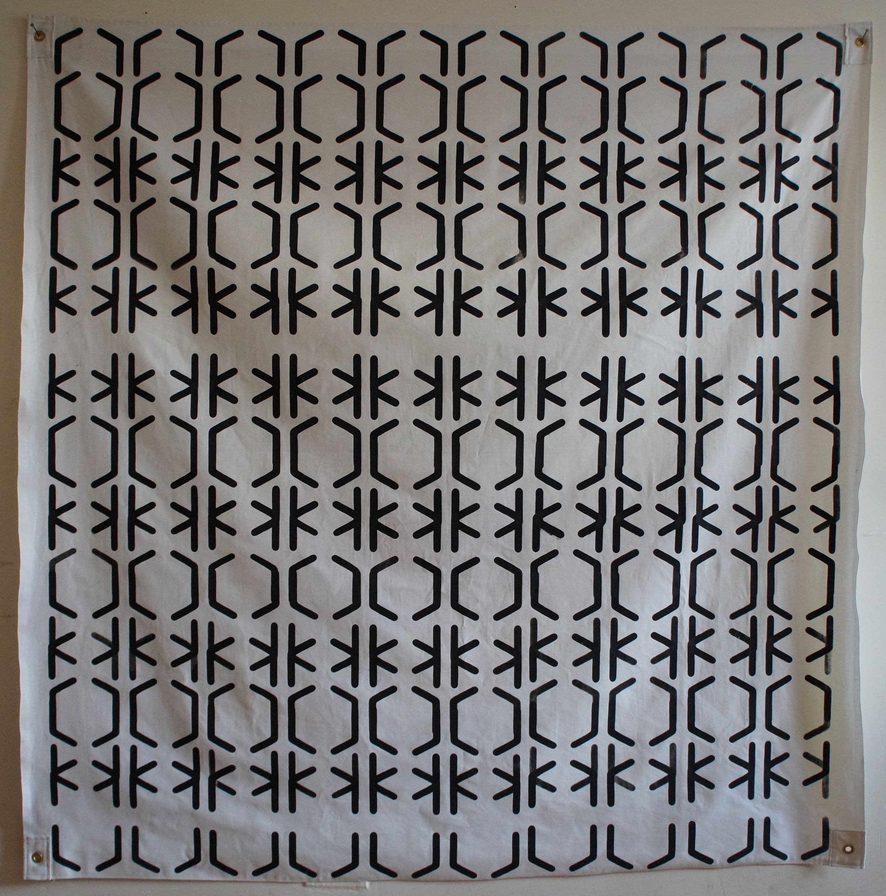a square canvas piece with grommets in each corner. lines create a shifting pattern
