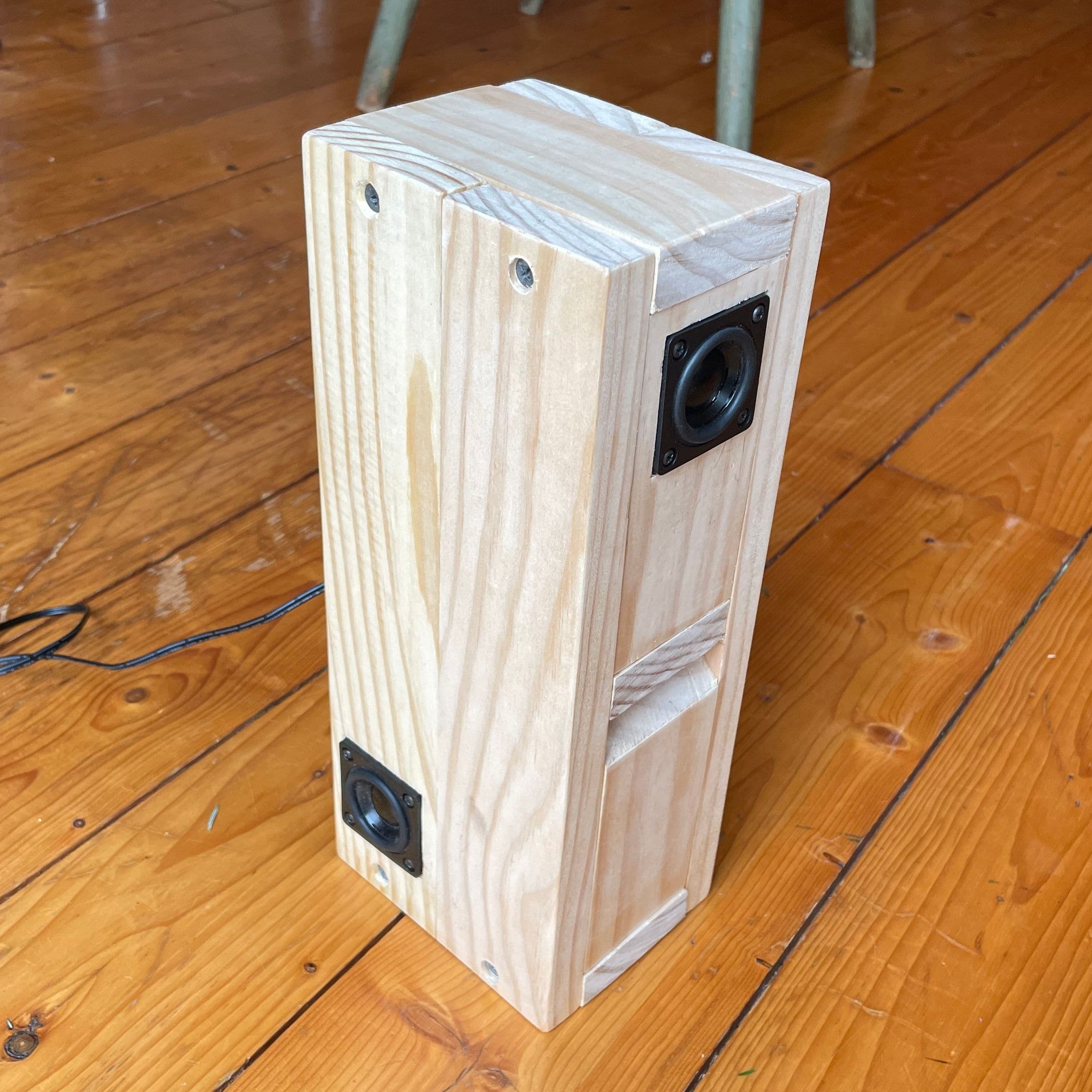 a hand made wooden box on a wooden floor, with two speakers on the top and side